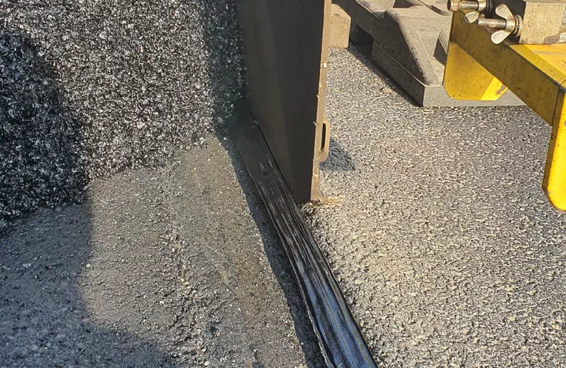 The paver working along the edge of the adjacent lane.